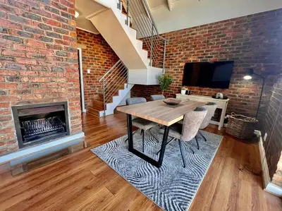a living room with a wooden table and a brick wall at Ben's Apartment in Stellenbosch