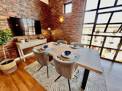 a dining room with a table and chairs and a brick wall at Ben's Apartment in Stellenbosch