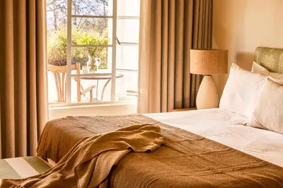 a bedroom with a bed and a window with a table at Boschendal Farm Estate in Franschhoek