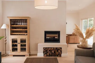 a living room with a fireplace and a wine cellar at Menuha Hermanus in Hermanus