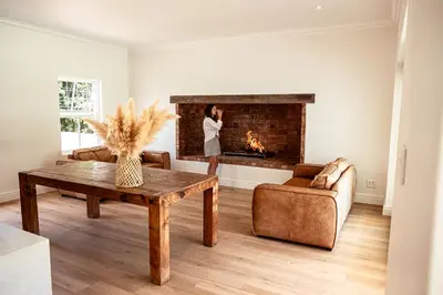 a woman standing in a living room with a fireplace at Menuha Hermanus in Hermanus