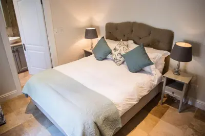 a bedroom with a white bed with blue pillows at Maison Des Huguenots Le Roux in Franschhoek