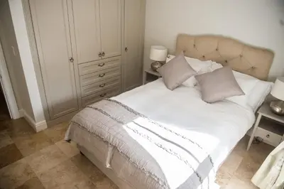 a bedroom with a bed with white sheets and pillows at Maison Des Huguenots Le Roux in Franschhoek