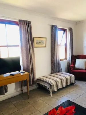 a living room with a bed and a chair and window at Bergsig Casa Guest House in Cape Town