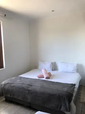 a large white bed with two pink towels on it at Bergsig Casa Guest House in Cape Town