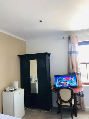 a bedroom with a desk with a computer and a chair at Bergsig Casa Guest House in Cape Town