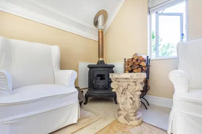 a living room with two chairs and a stove at Devon Castle Orchard Cottage in Stellenbosch