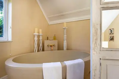 a white tub in a bathroom with a window at Devon Castle Orchard Cottage in Stellenbosch