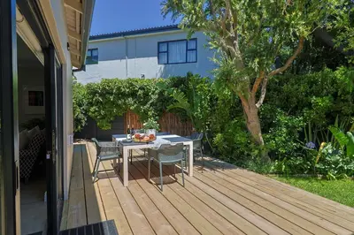 a wooden deck with a table and chairs on it at Saffron House in Hermanus
