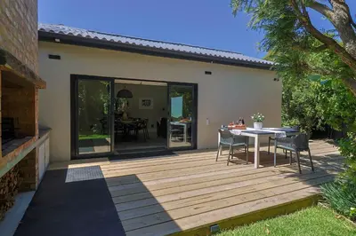 a wooden deck with a table and chairs on it at Saffron House in Hermanus