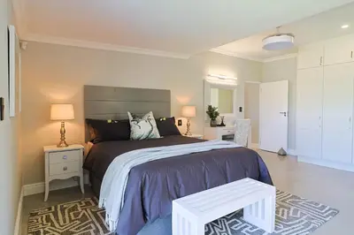 a bedroom with a large bed and a table at Saffron House in Hermanus