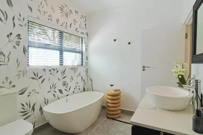 a bathroom with a large white tub and a window at Saffron House in Hermanus