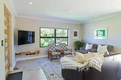 a living room with a couch and a tv at Saffron House in Hermanus