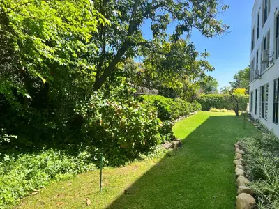 a garden with green grass and trees and a building at Designer Luxe Stellies Studio in Stellenbosch
