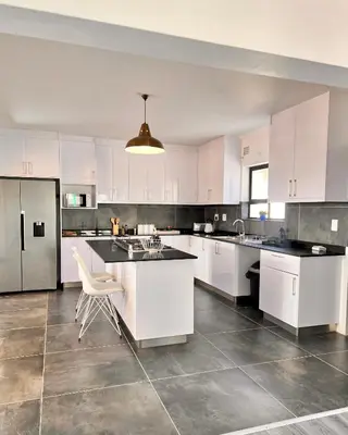a large white kitchen with white cabinets and appliances at 2nd on Strand in Cape Town