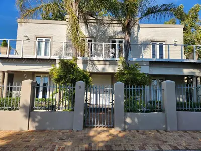 a white house with a gate and a palm tree at Stirling House in Paarl