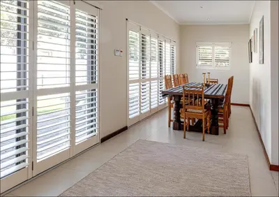 a dining room with a table and chairs and windows at Seabreeze in Hermanus