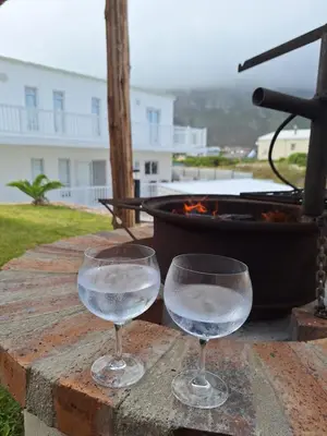two glasses of water sitting on a table with a grill at Nivenia Beach House in Bettyʼs Bay