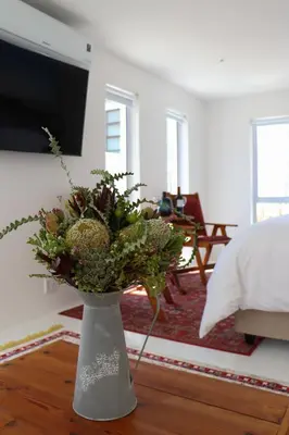 a white vase with flowers in a living room at Nivenia Beach House in Bettyʼs Bay