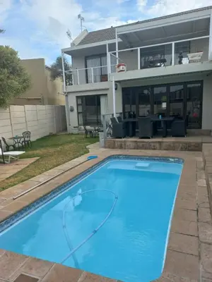 a large blue swimming pool in front of a house at Crystal Villa Guesthouse in Cape Town