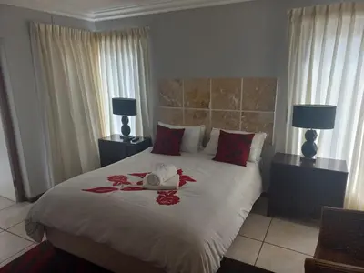 a bedroom with a large bed with red flowers on it at Crystal Villa Guesthouse in Cape Town