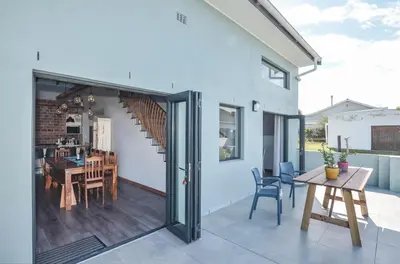 a patio with a table and chairs and a dining room at The Neighbours - Kleinmond in Kleinmond