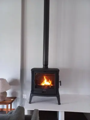 a fireplace in a living room with a fire at The Neighbours - Kleinmond in Kleinmond