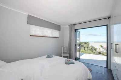 a bedroom with a white bed and a sliding glass door at The Neighbours - Kleinmond in Kleinmond