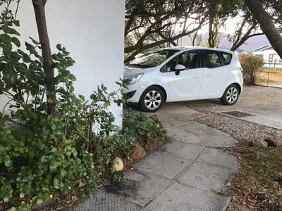 a small white car parked next to a building at Watercolour Cottage in Hermanus