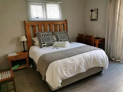 a bedroom with a large bed with black and white pillows at Hermanus 13 on 2nd Guest Rooms in Hermanus