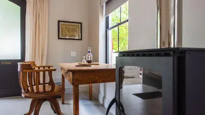a room with a wooden table and a chair and a table and a window at Franschhoek Colours in Franschhoek