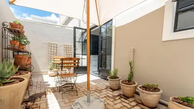 a patio with potted plants and an umbrella at Franschhoek Colours in Franschhoek