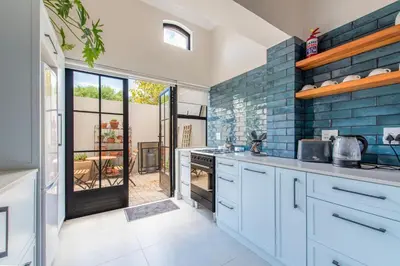 a kitchen with white cabinets and blue brick walls at Franschhoek Colours in Franschhoek
