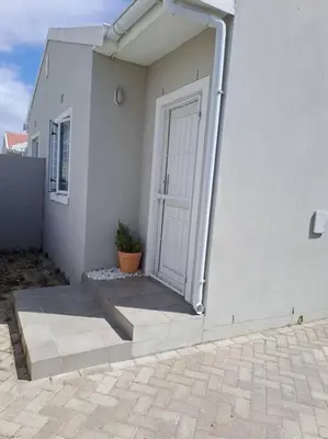 a white building with a door and a potted plant at Modest Home in Cape Town in Cape Town