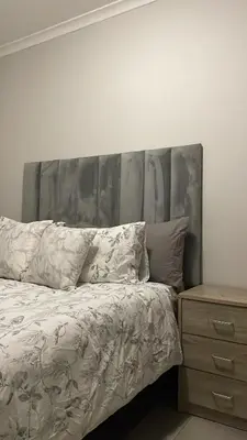 a bed with a silver headboard next to a dresser at Modest Home in Cape Town in Cape Town
