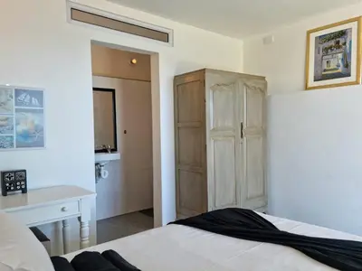 a bedroom with a bed and a wooden cabinet at 'BoStrand' - Private and Central, only 2 min walk to beach - sleeps 2 in Gordonʼs Bay