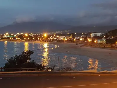 a view of a beach at night with lights at 'BoStrand' - Private and Central, only 2 min walk to beach - sleeps 2 in Gordonʼs Bay