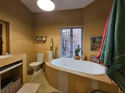 a bathroom with a tub and a toilet and a window at Cardamom Cottage, sleeps 3 and 1 min walk to beach in Cape Town