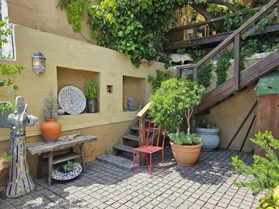a patio with a table and a staircase with plants at Cardamom Cottage, sleeps 3 and 1 min walk to beach in Cape Town