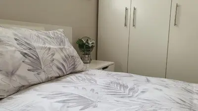 a bed with a white comforter with a plant on it at Hidden gem on Eksteen in Cape Town