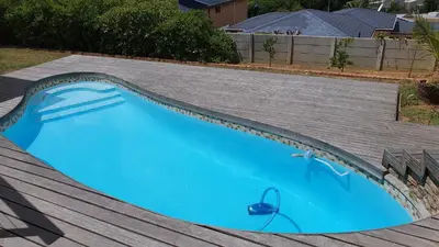 a blue swimming pool with a grey roof at Hidden gem on Eksteen in Cape Town