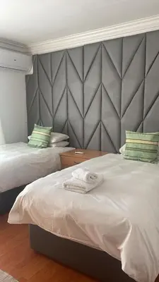 a bedroom with two beds and a headboard at The Other House - Cape Town in Cape Town