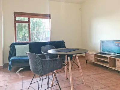 a living room with a table and chairs and a tv at Loft Cottage, sleeps 2. Central and Cozy! in Cape Town