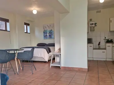 a bedroom with a bed and a table and chairs at Loft Cottage, sleeps 2. Central and Cozy! in Cape Town