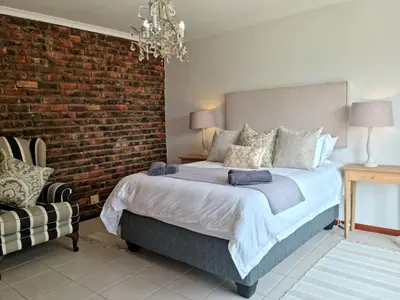 a bedroom with a bed and a brick wall at '79 Protea' Charming self-catering Home, sleeps 6 with Sea Views in Gordonʼs Bay