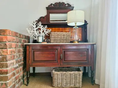 a wooden dresser with baskets on it next to a brick wall at '79 Protea' Charming self-catering Home, sleeps 6 with Sea Views in Gordonʼs Bay