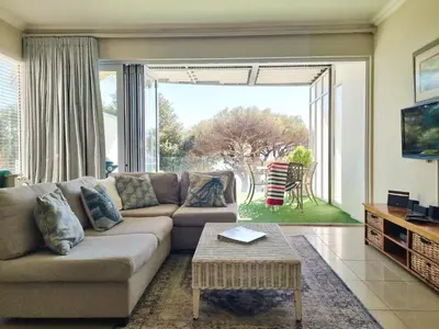a living room with a couch and a large window at Beach Apartment on Bikini Beach - sleeps 4 in 2 Ensuite Bedrooms in Cape Town