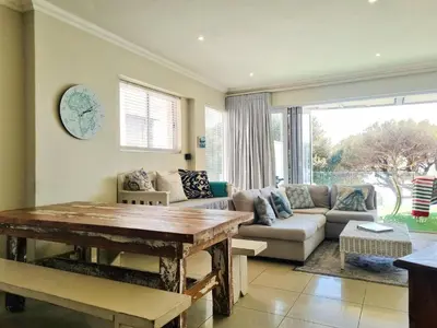 a living room with a couch and a table at Beach Apartment on Bikini Beach - sleeps 4 in 2 Ensuite Bedrooms in Cape Town