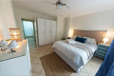 a bedroom with a large bed with a ceiling fan at 'Ocean Views', Modern, Spacious Home, 3 En-suite Bedrooms in Cape Town