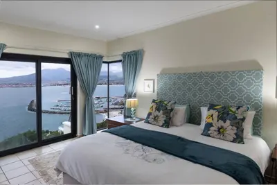 a bedroom with a bed with a view of the water at 'Ocean Views', Modern, Spacious Home, 3 En-suite Bedrooms in Cape Town